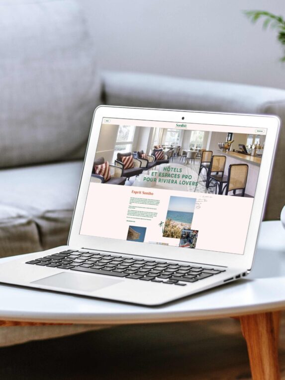 Page d’accueil du site internet du groupe hôtelier Soniho. Un ordinateur portable apple est ouvert et posé sur une table basse blanche dans un salon moderne composé d’un canapé gris.