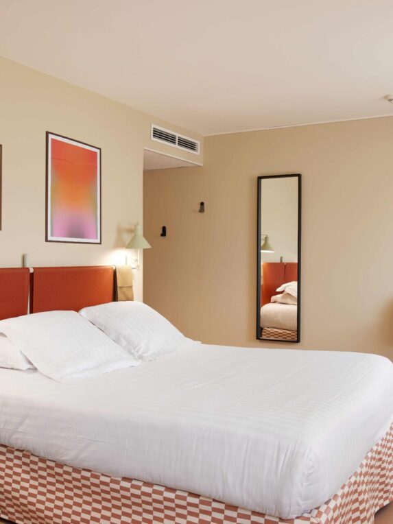 Chambre double de l’hôtel des Victoires à Cannes la Bocca dans le Sud de la France sur la Côte d’azur. Un lit moderne avec une décoration épurée et minimaliste aux couleurs ocres et beiges.