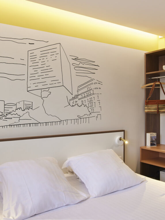 Modern, streamlined hotel room at the Hotel du Pin with designer wall art, practical storage and coffee corner - a comfortable, stylish space for a business or leisure stay.
